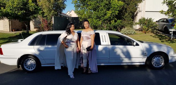 A photo of two women dressed formally in front one of our limousines