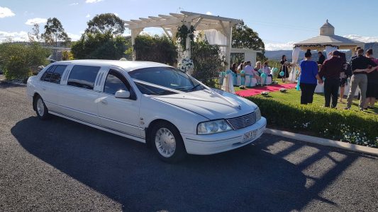 A photo of one of our limousines by a gorgeous outdoor Wedding front of car