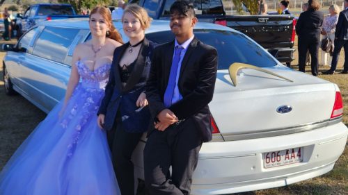 Three well-dressed youth standing in front of our 9 seater Limo at a school formal in 2023.